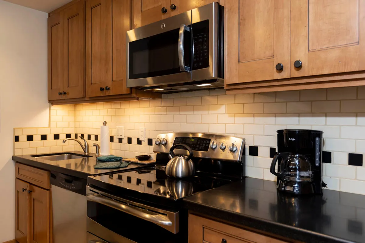 A well-equipped kitchen with stainless steel appliances, wooden cabinetry, and a coffee maker, ready for preparing breakfast or dinner. The practical, inviting setup encourages home-cooked meals and socializing around food.